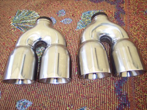 2006 Chevrolet Corvette - These chrome quad exhaust mufflers are shown from an angled perspective against a patterned rug.