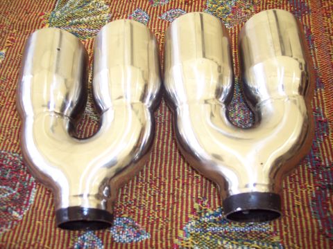 2006 Chevrolet Corvette - Pair of chrome exhaust tips with U-shaped pipes shown on a patterned surface.
