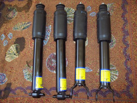 2006 Chevrolet Corvette - Four new shock absorbers are displayed on a patterned surface, ready for installation.