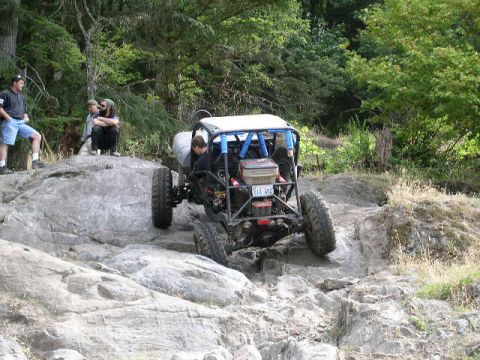1979 Ford Bronco - An off-road buggy navigates a rocky trail with spectators observing the action.