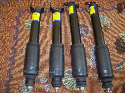 2006 Chevrolet Corvette - Four black shock absorbers are laid out on a patterned rug. The registry claims they are from a 2006 Chevrolet Corvette Z06.