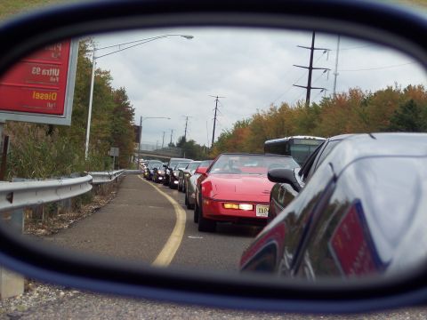 2006 Chevrolet Corvette - A convoy of C4 Chevrolet Corvettes drives down a road, seen in a side mirror.