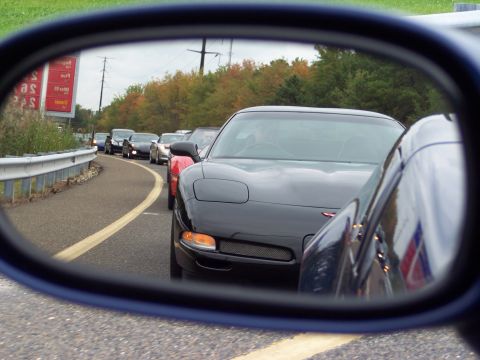 2006 Chevrolet Corvette - A line of cars, including a black Corvette, are stopped on a road, as seen from a side-view mirror.
