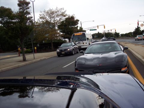 2006 Chevrolet Corvette - A black Chevrolet Corvette is seen in traffic, with other vehicles and a bus in the background.