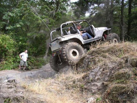1979 Ford Bronco - An off-road vehicle navigates a challenging rocky terrain, with a bystander observing the ascent.