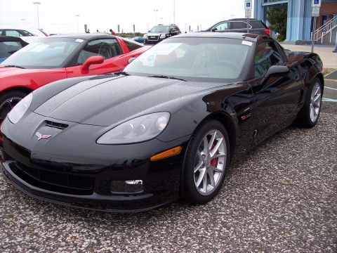 2006 Chevrolet Corvette - A black Chevrolet Corvette is parked in a lot next to a red sports car.