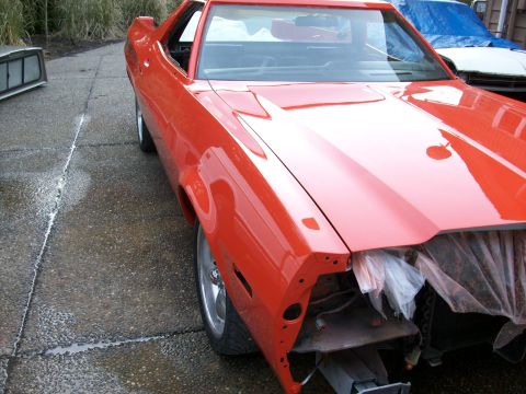 1973 Ford Ranchero - A bright red coupe utility vehicle is parked outside, with its front end disassembled and covered with plastic sheeting.