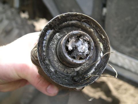 1979 Ford Bronco - A heavily soiled driveshaft U-joint is held for inspection.