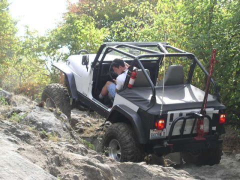 1979 Ford Bronco - A white Jeep Wrangler navigates a challenging rocky incline on an off-road trail.