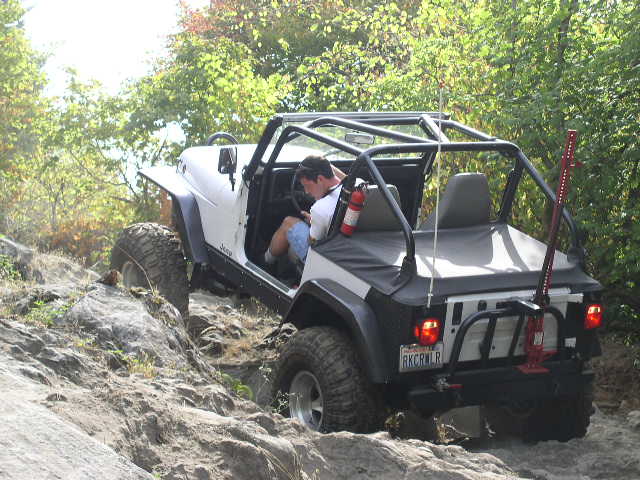 White topless Jeep Wrangler with roll cage crawling down rocks, RKCRWLR plate