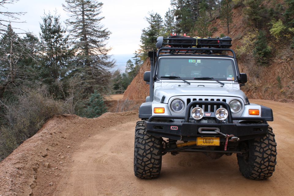 Silver 2003 Jeep TJ with roof rack and winch on a dirt road
