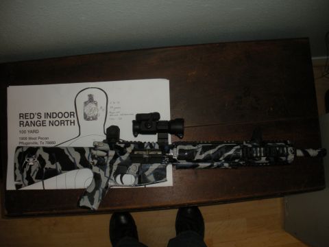1996 Ford Bronco - A rifle with a distinctive tiger stripe camouflage pattern is displayed next to a shooting target from Red's Indoor Range North.