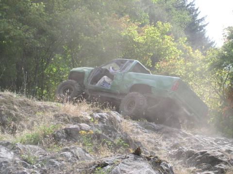 1979 Ford Bronco - A modified green truck navigates a challenging rocky terrain off-road.