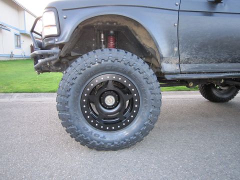 1996 Ford Bronco - Close-up of a modified black Ford Bronco's front wheel and suspension system.