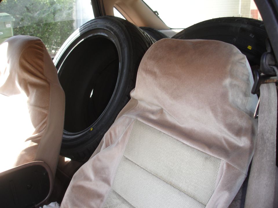 Car interior with two tires stacked behind the front seats, covered with tan fabric