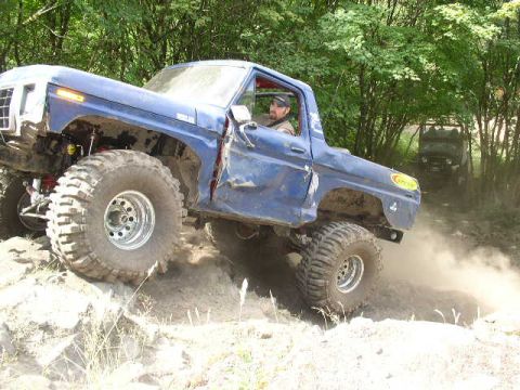 1979 Ford Bronco - Modified 1979 Ford Bronco navigates an off-road trail, kicking up dust.