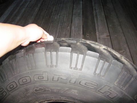 1986 Ford Bronco - A hand presses on the sidewall of a BFGoodrich Baja T/A tire, showing its tread pattern.