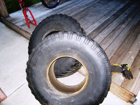 1986 Ford Bronco - Two BFGoodrich Baja T/A tires are shown on a wooden deck, with a pair of work gloves nearby.