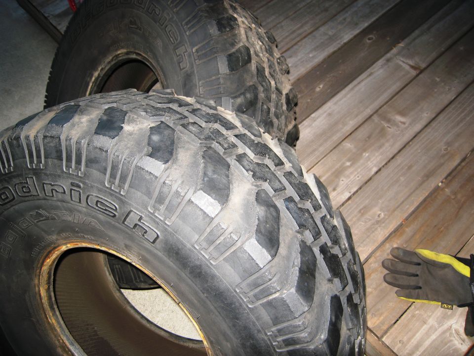 Two BFGoodrich Mud-Terrain T/A tires stacked, one in front of the other. Wood paneling in background