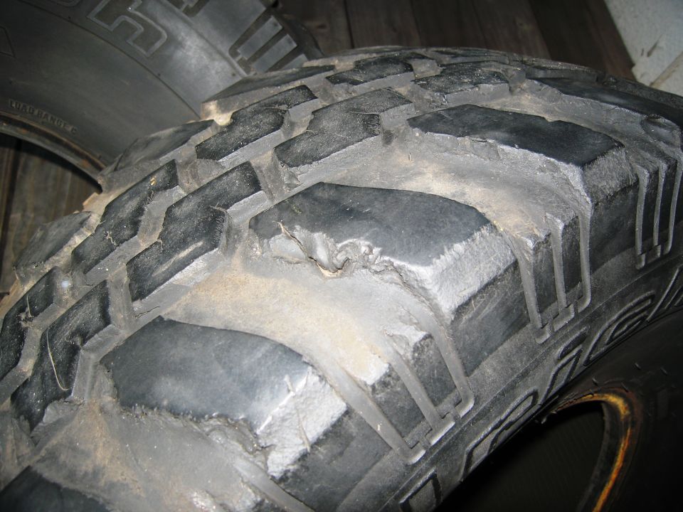 Close-up of a worn off-road tire with aggressive tread. Text on the sidewall is partially visible