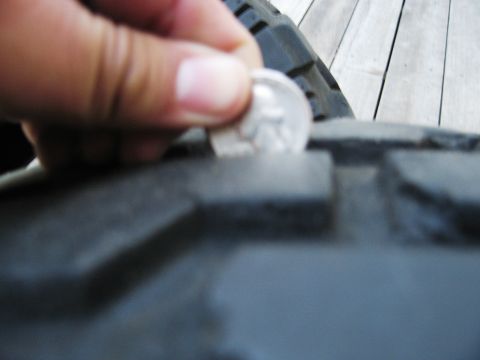 1986 Ford Bronco - A dime is used to check the tread depth on a tire, indicating wear.