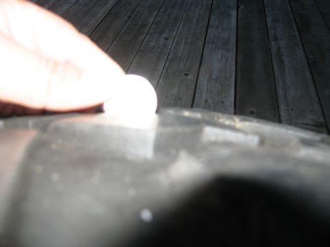 1986 Ford Bronco - A finger presses down on a tire tread, with a wooden deck visible behind.