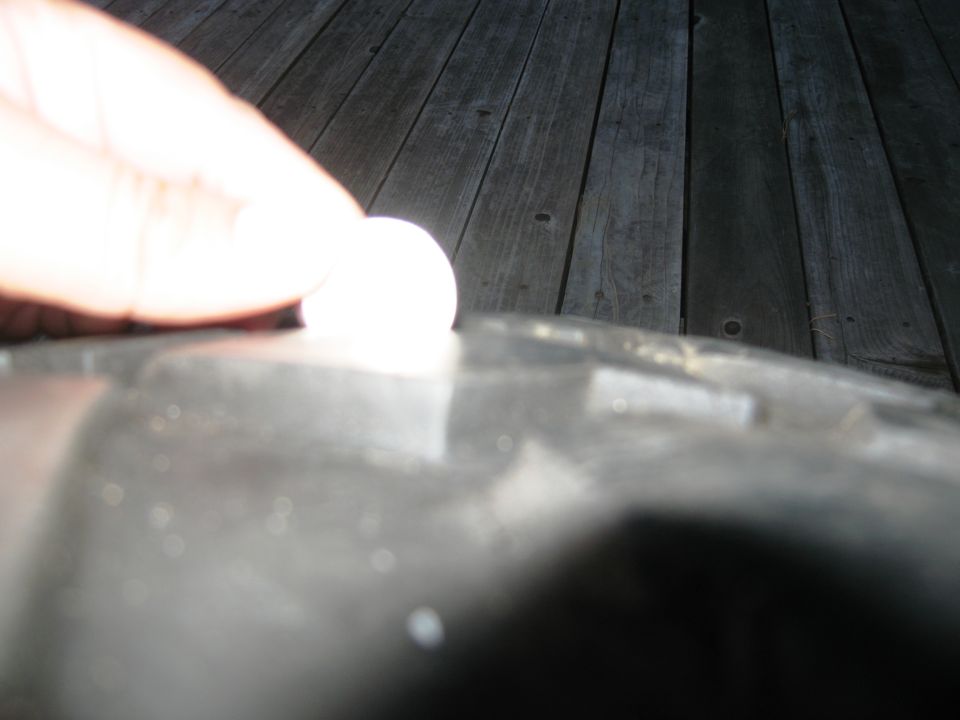Close-up of a tire tread with a finger pressing on it. Wooden planks in background
