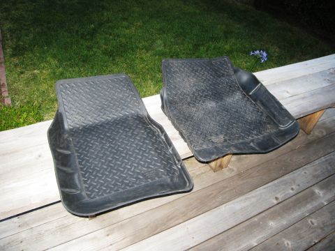 1986 Ford Bronco - Two black rubber floor mats with a diamond tread pattern are placed on a wooden deck.