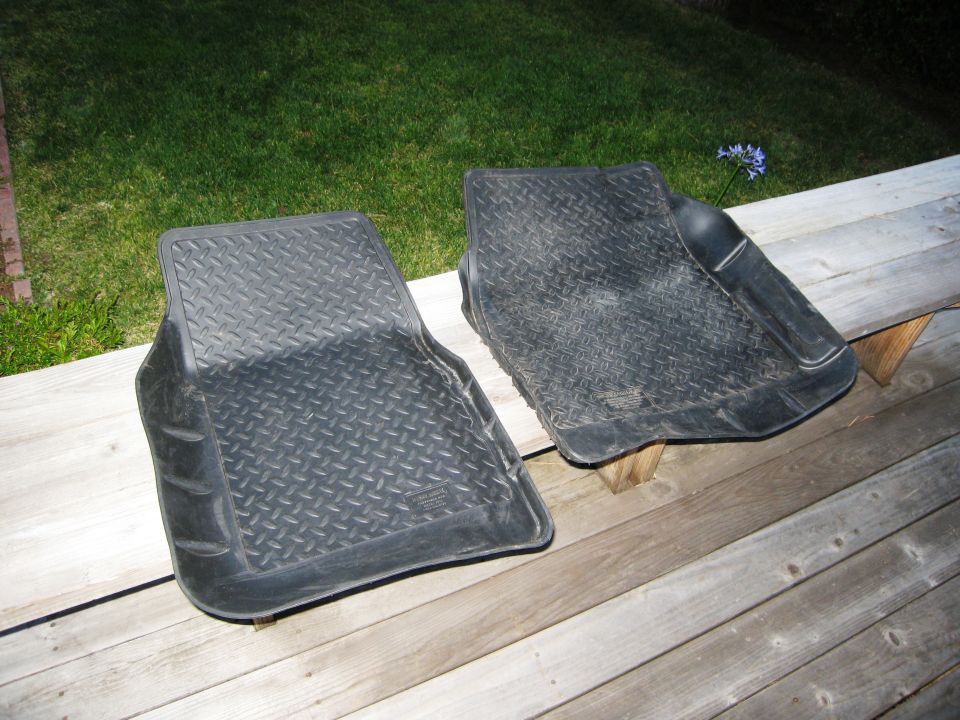 Two black diamond-tread rubber floor mats on a wooden deck