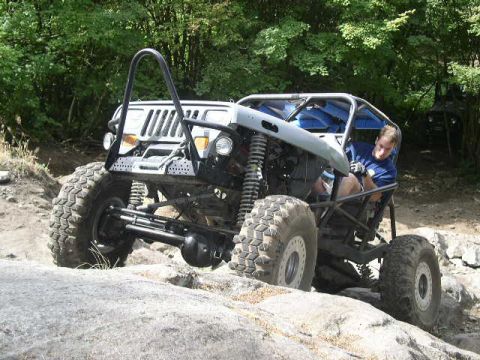 1979 Ford Bronco - A custom off-road buggy navigates a rocky trail with a second vehicle in the background.