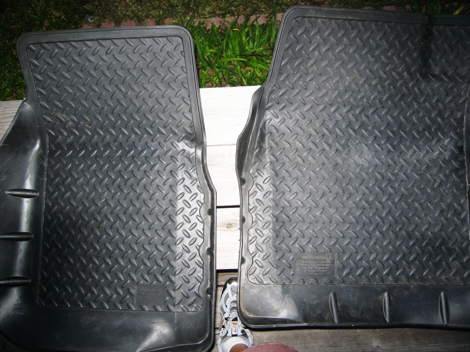 Two black rubber floor mats with diamond tread pattern, one partially obscuring the other