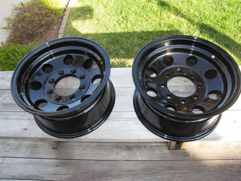 1986 Ford Bronco - Two black steel wheels are shown resting on wooden planks outdoors.