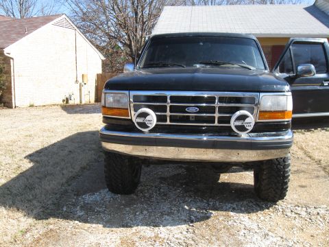 1994 Ford Bronco - Front view of a black 1994 Ford Bronco, auxiliary lights on the bumper and a prominent Ford grille.