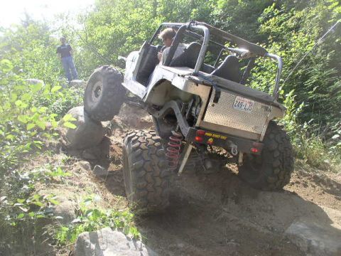 1979 Ford Bronco - An off-road vehicle navigates a challenging rocky terrain, with one wheel lifted high as it climbs.