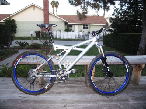 1986 Ford Bronco - Full-suspension mountain bike with blue rims parked on a wooden deck in front of a house.