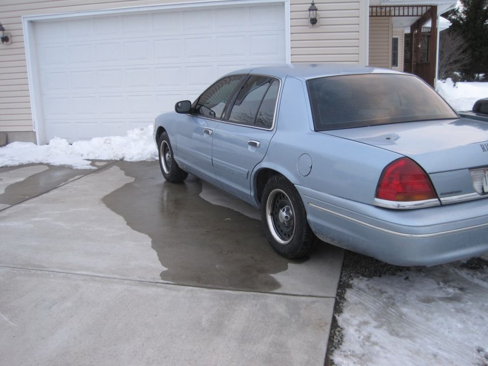 Light blue sedan parked on a wet driveway in front of a garage