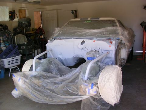 1972 Ford Ranchero - A car is covered in plastic sheeting in a garage, likely for painting or repairs.