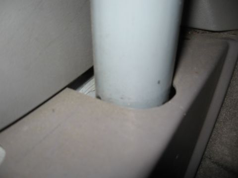 1994 Ford Bronco - Close-up inside a vehicle showing a light gray tubular post passing through a notched cut-out in a mauve-gray plastic interior trim panel,…