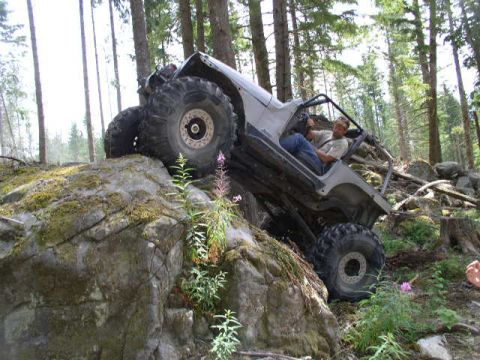 1979 Ford Bronco - Off-road Jeep Wrangler navigating a challenging rocky terrain on a forest trail.