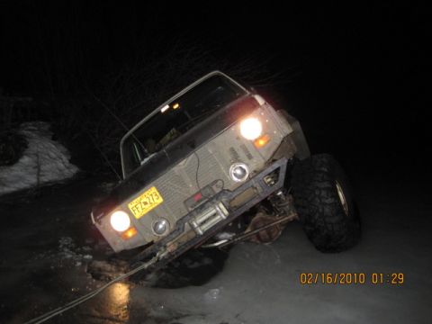 1990 Ford F-250 - A pickup truck lies on its side in the dark, its headlights still illuminated.
