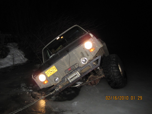Overturned pickup truck on its side at night, headlights on