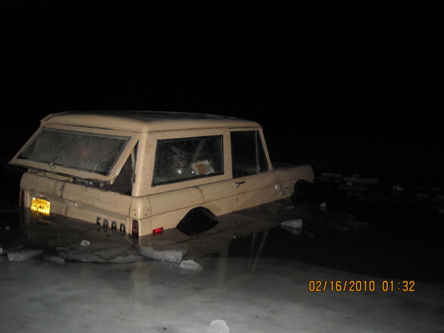 Tan SUV parked at night, rear view. License plate is visible but unreadable