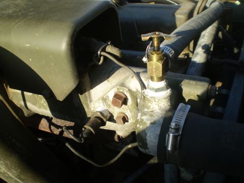 2005 Ford Excursion - Close-up view of the engine bay, focusing on a brass valve and hoses connected to the water pump housing.