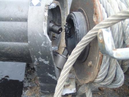 1996 Ford Bronco - Close-up of a failed winch with its cast housing cracked and broken away at the drum end, exposing the output shaft and torn-up internals.…