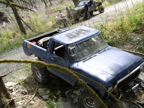 1979 Ford Bronco - A blue 1978 Ford Bronco is parked on a dirt trail, with another off-road vehicle visible in the background.