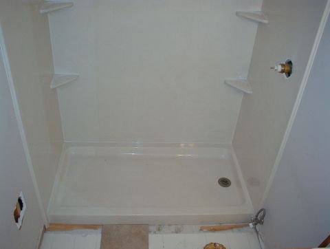 2004 Land Rover Land Rover - A newly installed shower stall with shelves and a drain is shown, with some unfinished wall and floor visible.