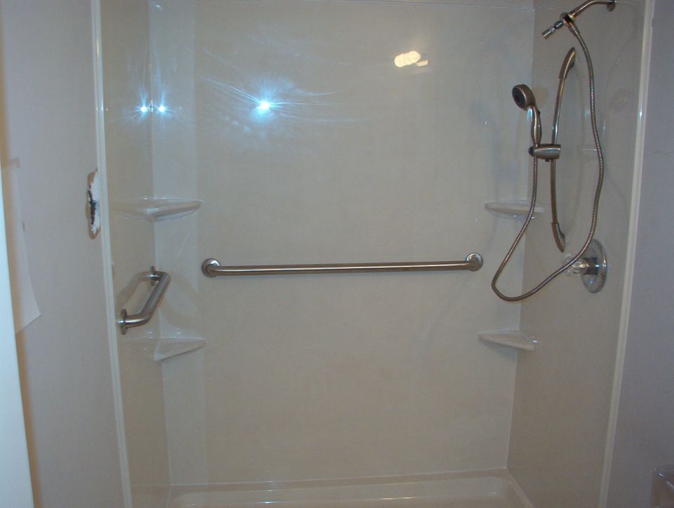 Shower stall interior with brushed nickel grab bars and handheld shower head