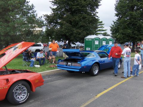 1978 Pontiac Trans Am - Two Pontiac Trans Ams, one blue and one red, are displayed with their hoods and trunks open at an outdoor event.