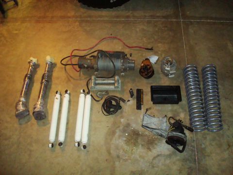1995 Ford Bronco - Various vehicle components, including winches, shocks, and springs, are displayed on a concrete surface.