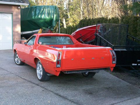 1973 Ford Ranchero - The rear of a red 1972 Ford Ranchero with custom wheels is visible, parked in a driveway.